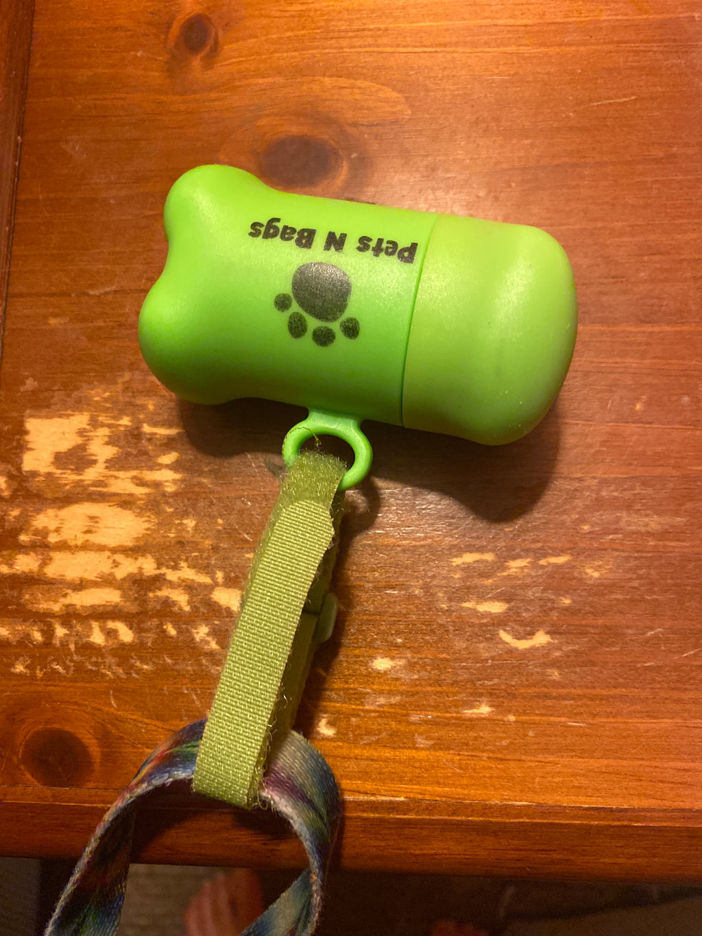 Green bone-shaped poop bag dispenser attached to a dog leash